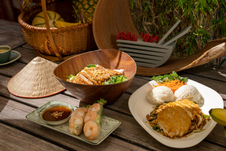 Vietnamesische Gerichte mit Sommerrollen, Bowl und Reis auf einem Holztisch